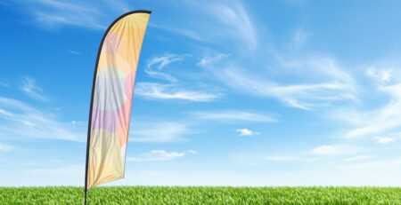 Outdoor teardrop banner, vibrant fabric, clear sky, green grass.
