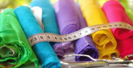 Rolls of colorful fabric, a measuring tape, and scissors.