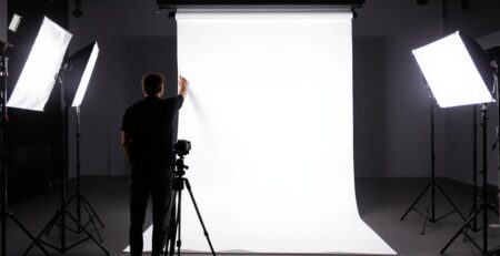 Fotógrafo ajustando un gran telón de fondo blanco con luces.