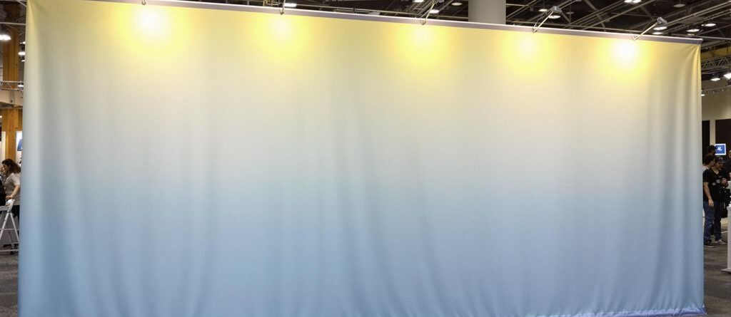 Brightly lit, vibrant tension fabric display in a large event space.