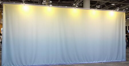 Brightly lit, vibrant tension fabric display in a large event space.