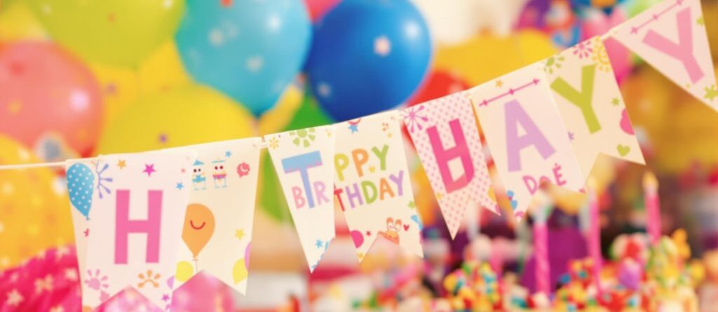 Colorful birthday banner, balloons, and cake.