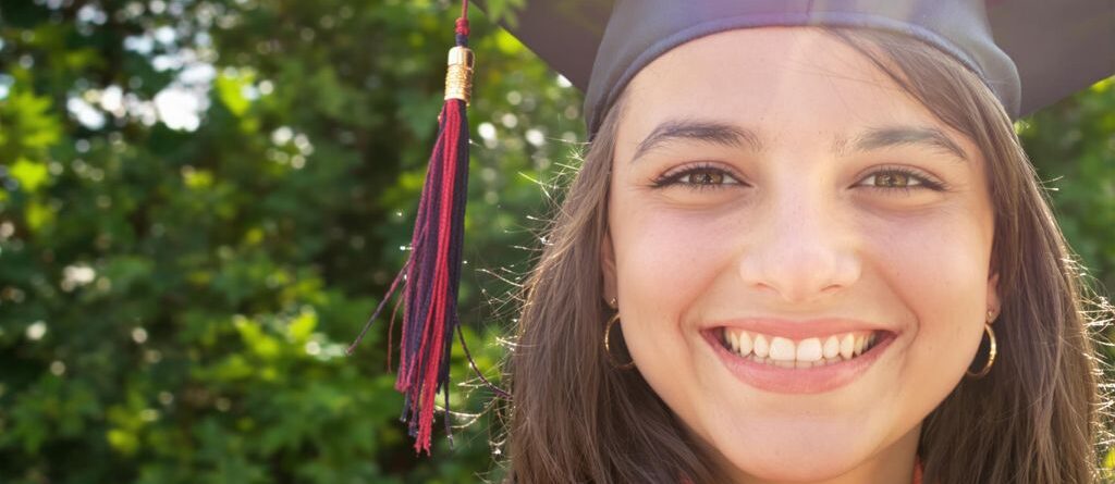 Graduado feliz sosteniendo una pancarta personalizada al aire libre.