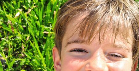 Smiling grad's face on a sunny lawn.