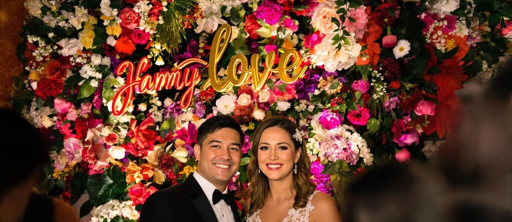 Couple laughing in front of a personalized floral backdrop.