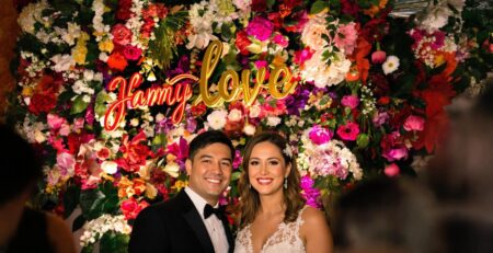 Couple laughing in front of a personalized floral backdrop.