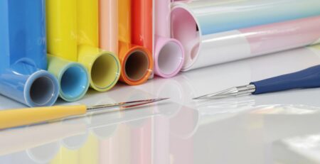 Colorful vinyl rolls, cutting tools, smooth application on surface.