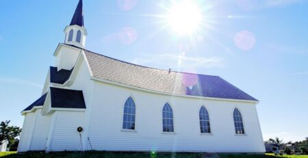 Bright sky, green grass, brick building, tall steeple