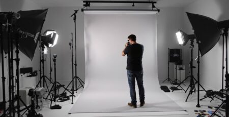 Photographer adjusts portable backdrop stand in studio.